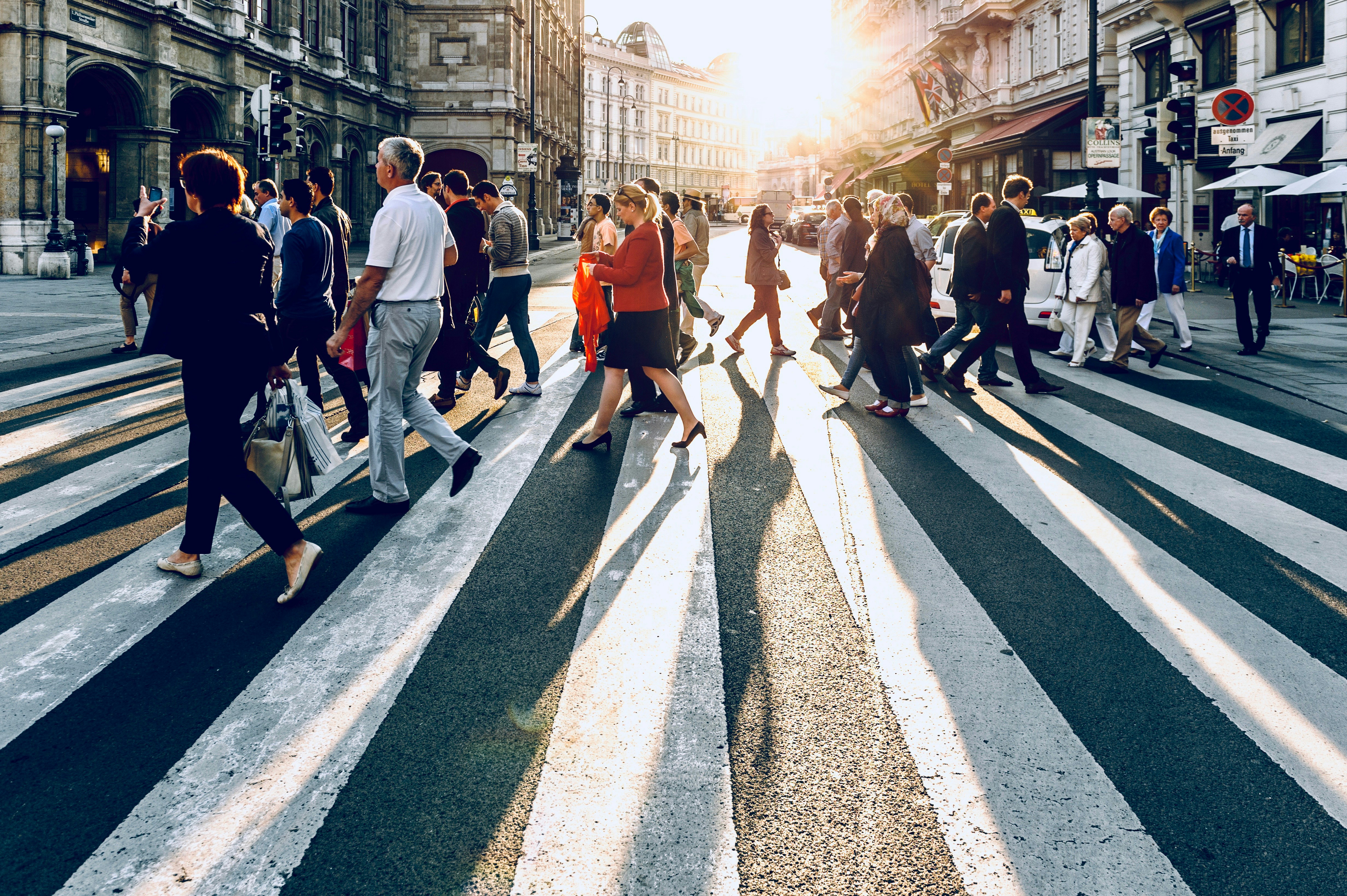 Crowd crossing a zebra crosswalk in strong backlight